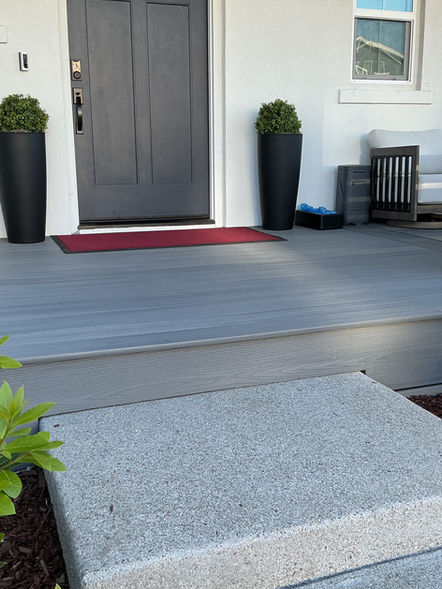 Modern front porch with Beach House Grey Fiberon composite decking, a large concrete step, and black tall planters next to a dark grey front door in Bethel Island.