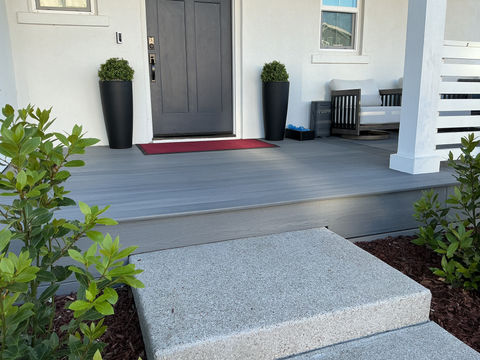 Modern front porch with Beach House Grey Fiberon composite decking, a large concrete step, and black tall planters next to a dark grey front door in Bethel Island.