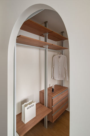 Minimalist closet with wooden shelves and hanging shirt.