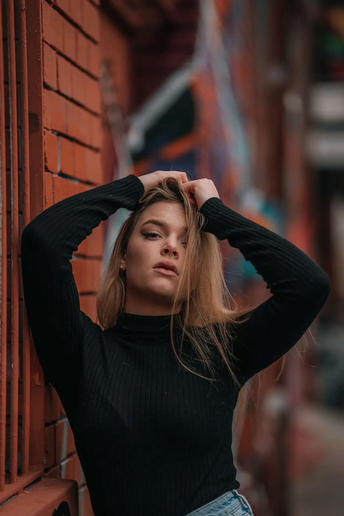 Frau mit Blonden Haaren steht auf einem Alten Fabrikgelände und hält ihre haare fest