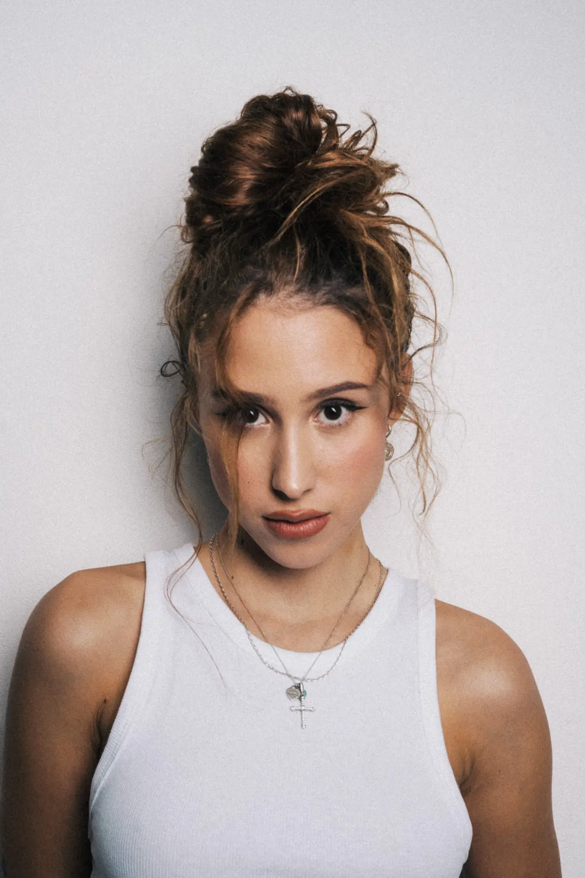 portraitaufnahme von Frau die an der Wand steht mit Braunen Haaren