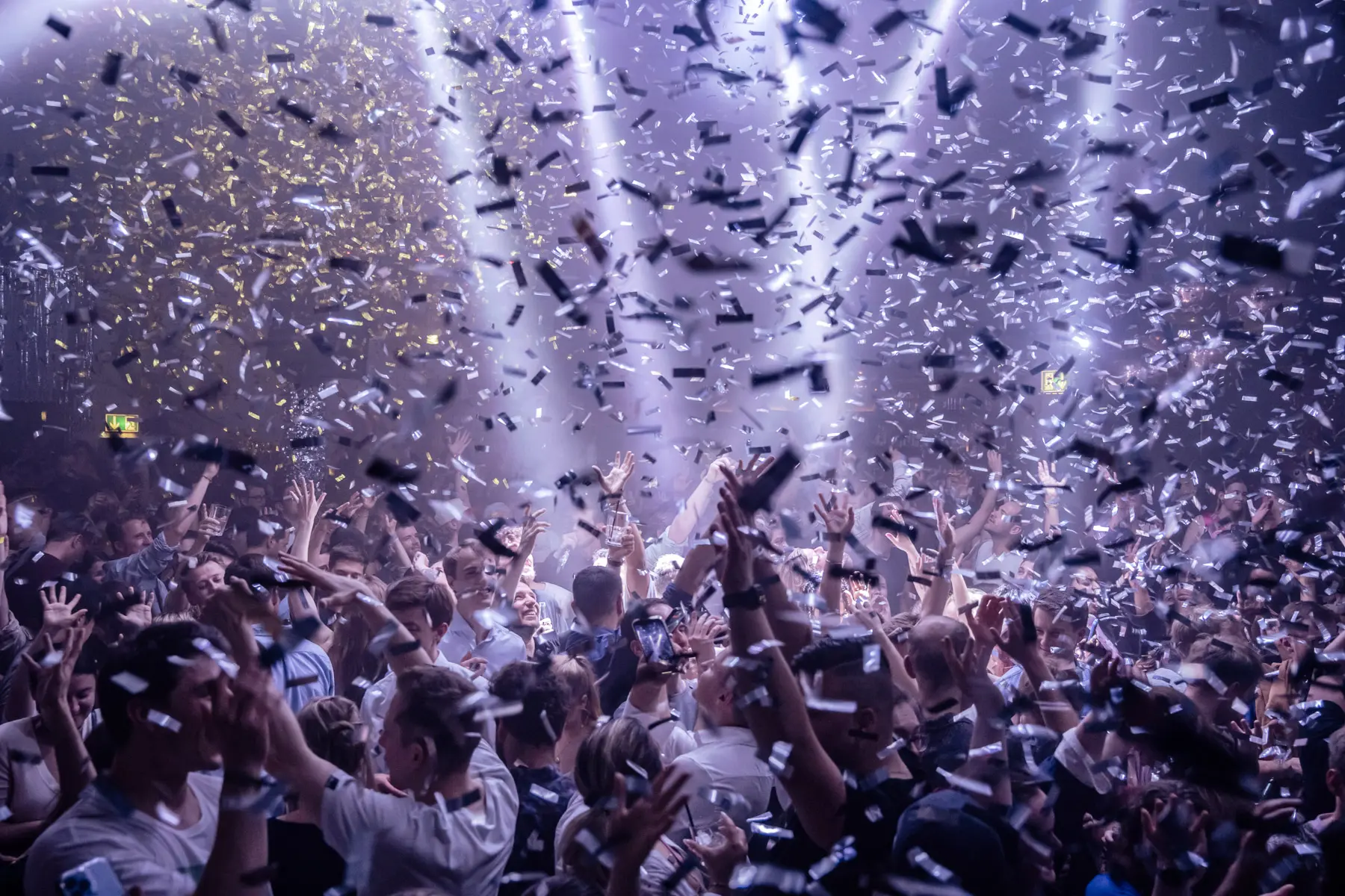 Voller Nachtclub mit viel konfetti, hände in der Luft