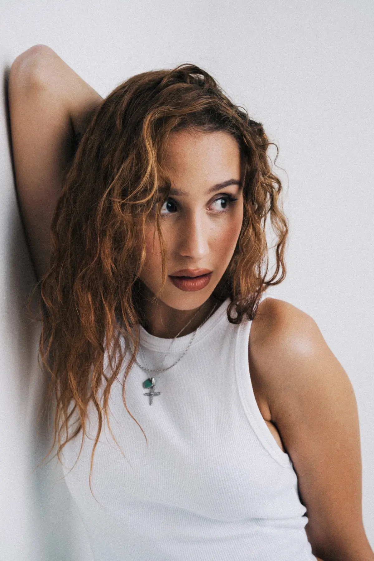 portraitaufnahme von Frau die an der Wand anlehnt und auf die Seite schaut