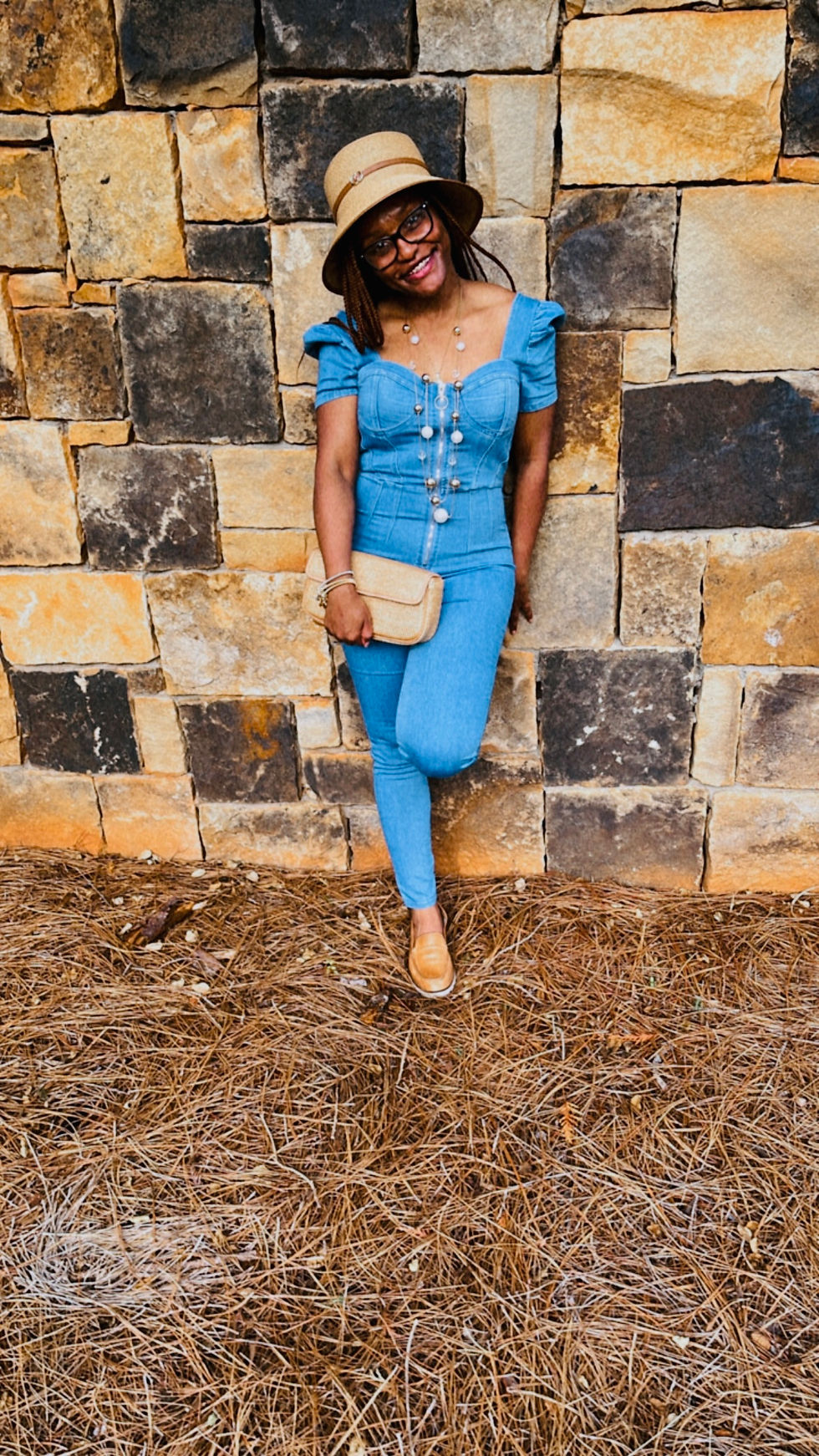 Thumbnail: Picture of model wearing Square Neck Denim Jumpsuit with a clutch handbag.