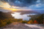 A lake in the mountains with a sunrise in the sky above