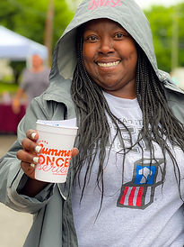 Young African American woman with long braids, smiling and holding a Summer Concert Series cup
