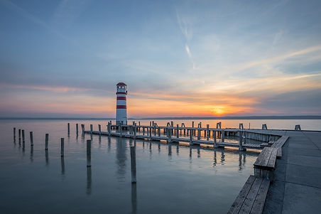 Canva - Dock and lighthouse at sunset.jpg