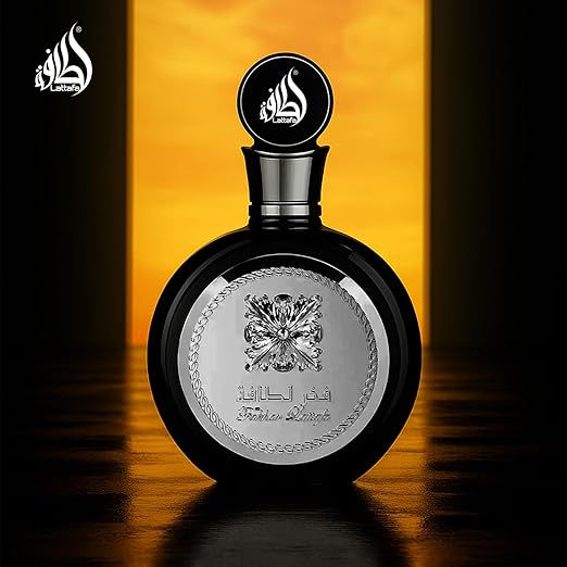 Frasco de perfume preto com tampa redonda, em frente a fundo alaranjado. Logo e inscrições decoram o frasco em prata, transmitindo luxo.