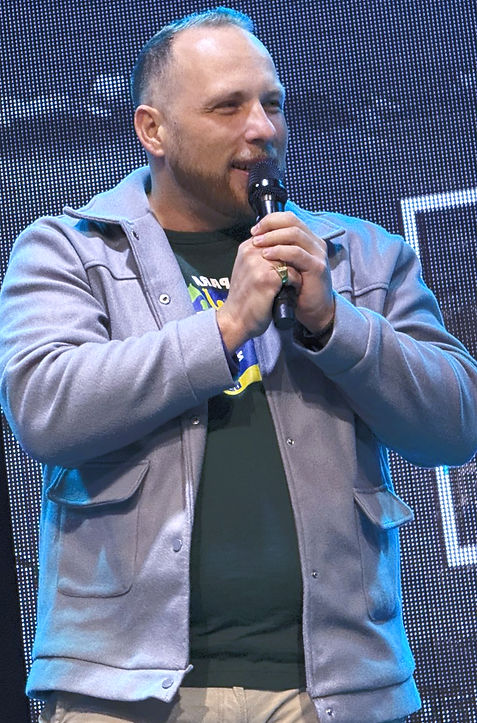 Gabriel Rocha no palco segurando um microfone apresentando uma palestra