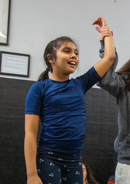 Young girl smiles, training martial arts with arms raised. Active training in gym