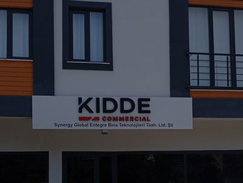 Kidde Commercial bina girişi üzerine uygulanan, beyaz alüminyum fon zeminli, siyah ve kırmızı 3D kabartma kutu harf tabela tasarımı.