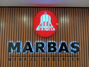 Akustik ahşap panel duvar kaplaması üzerine monte edilmiş arkadan file LED aydınlatmalı siyah kutu harf ve dairesel kırmızı pleksi logo uygulaması.
