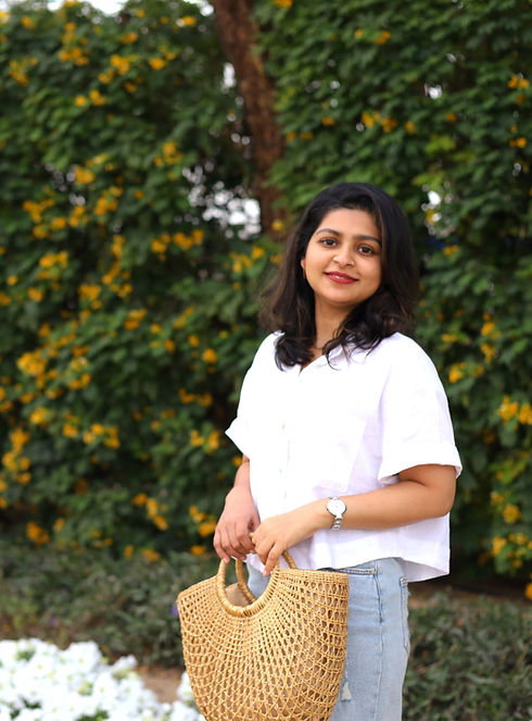 Seba Mary Thomas founder of ELA - The Eco Store smiling outdoors holding a natural seagrass moon bag — eco friendly home decor UAE