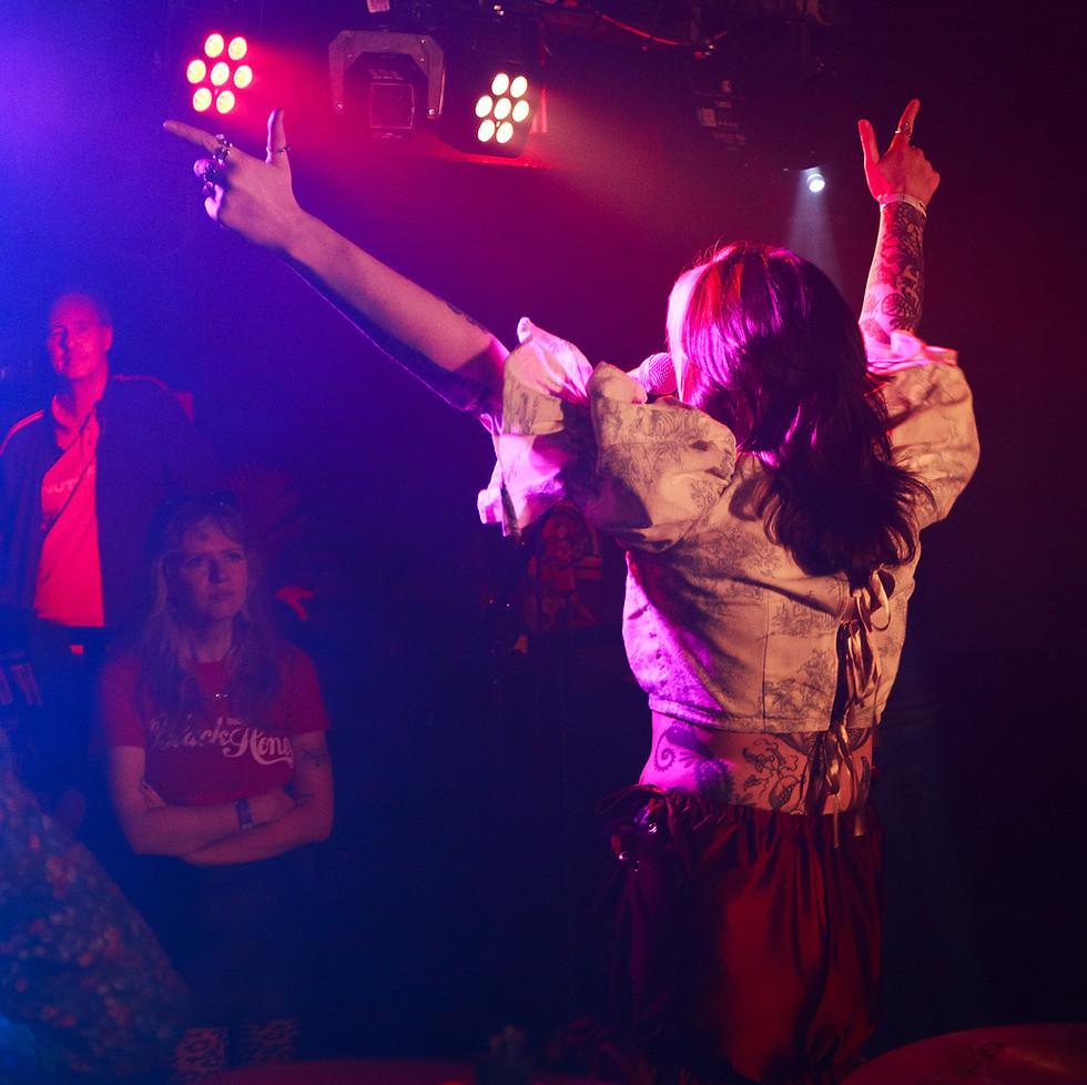 A lively band shot of a female vocalis throwing her hands in the air.