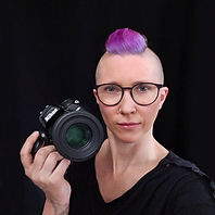 Jessy holding camera with purple hair and glasses