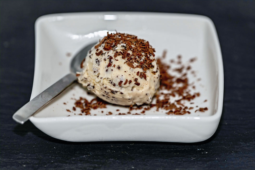 Kugel Stracciatellaeis in einer weißen Schale, bestreut mit Stracciatellastückchen.