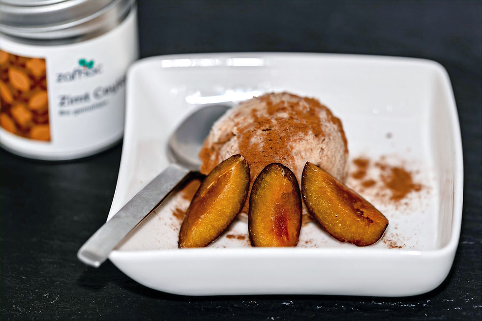 Kugel Zwetschgen-Zimteis in einer weißen Schale, umgeben von Zwetschgen und mit Zimt bestreut.