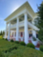 Large white colonial-style home with painters working on tall columns and porch