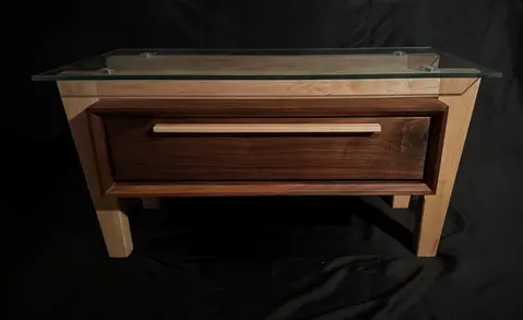 Front view of a mid-century modern coffee table with a suspended walnut rectangular box, supported by tapered maple legs and stretchers.