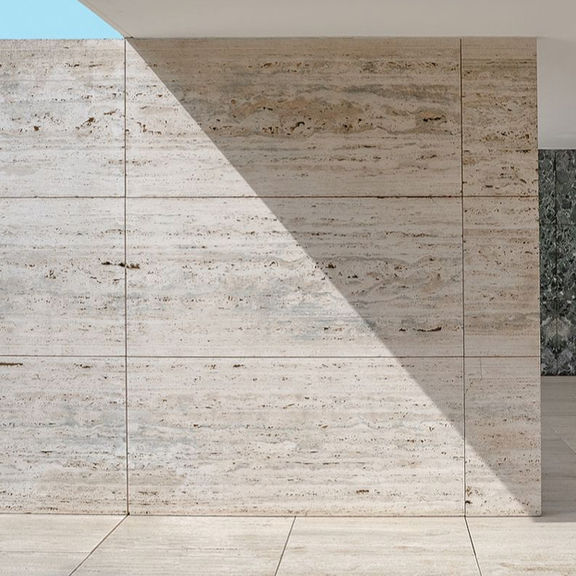 Exterior view of a modern building facade clad in vein-cut Argent Grigio Travertine panels under sharp sunlight.