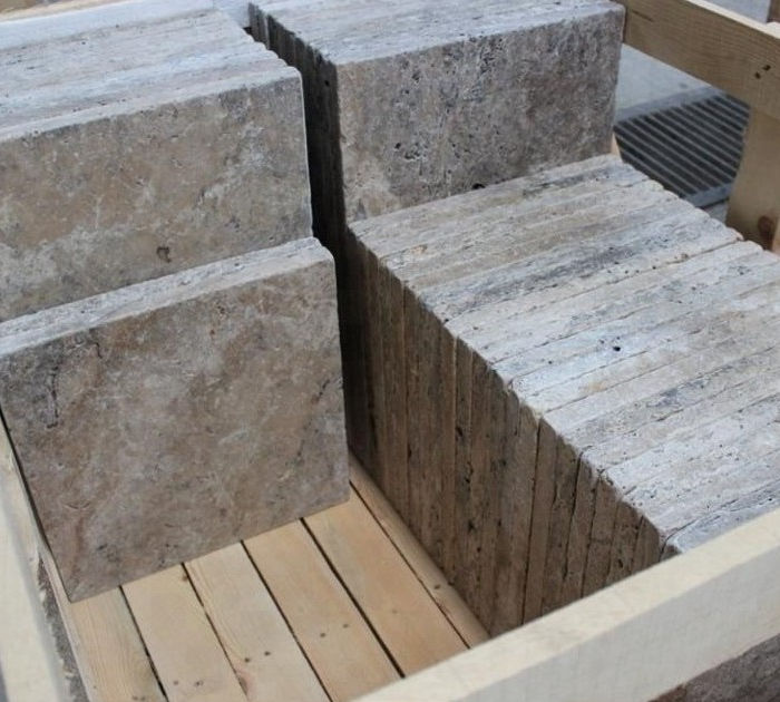 Heavy rectangular blocks of grey Titanium Travertine resting on wooden pallets in a stone yard.