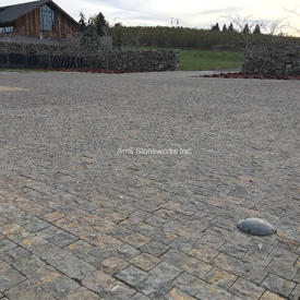 Split cobblestone parking lot paving using rich, earthy Montipora Limestone laid out in a custom radial geometric design.