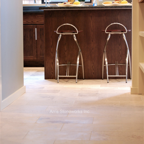 Warm neutral limestone flooring in a modern kitchen setting, featuring a smooth honed finish.