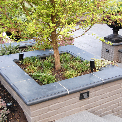 Modern raised garden planters at the Medina Residence featuring honed Obsidian Basalt wall caps and split-face stone cladding.