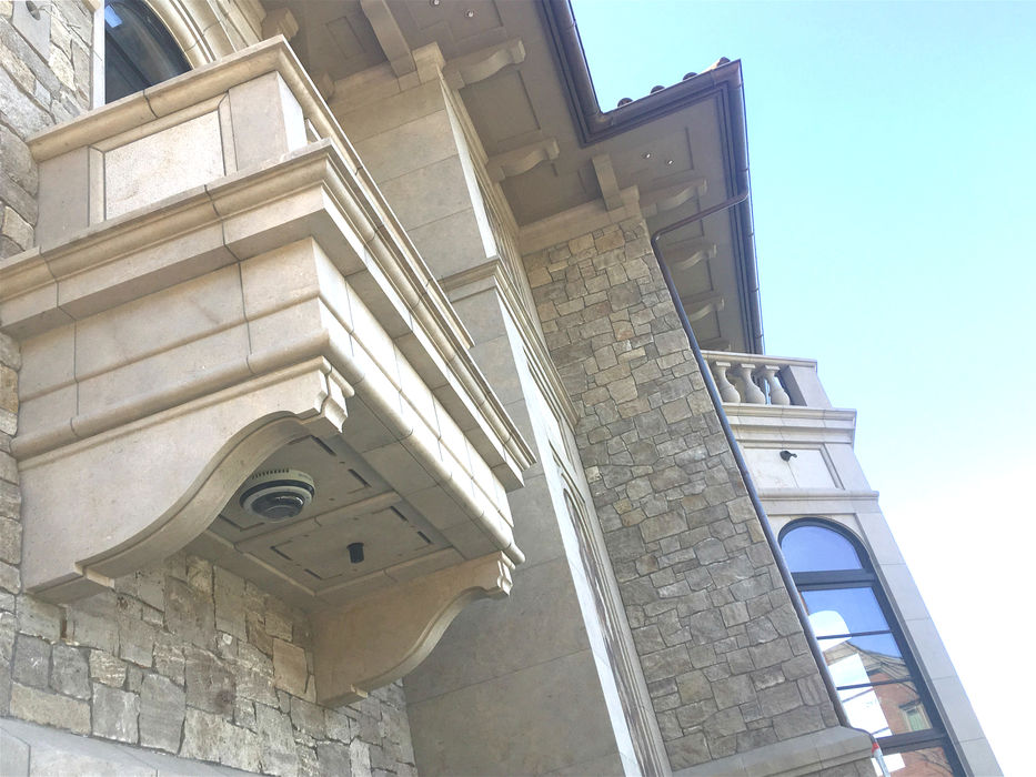 An elegant exterior balcony on a luxury estate featuring custom-fabricated Glenn Limestone architectural cornice details and a classic stone balustrade
