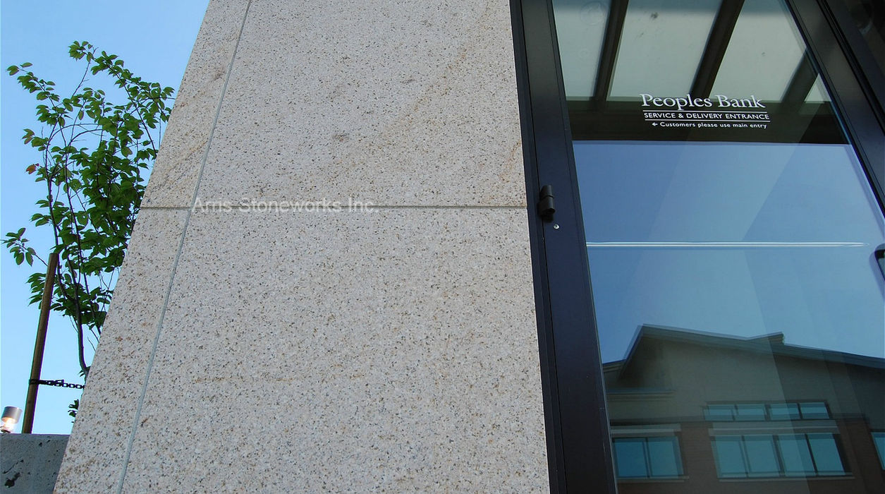 Close-up of People's Bank exterior showing honed Sorrel Granite wall panels and precision-fitted stone corners.