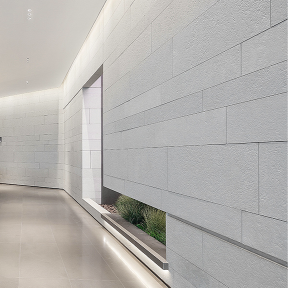 Minimalist interior corridor with backlit, smooth sandblasted Dove Grey Limestone wall panels and polished flooring.