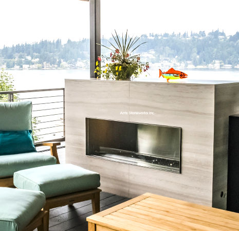 Exterior patio featuring Obsidian Basalt pavers and White Wood Vein Limestone wall cladding overlooking the water.