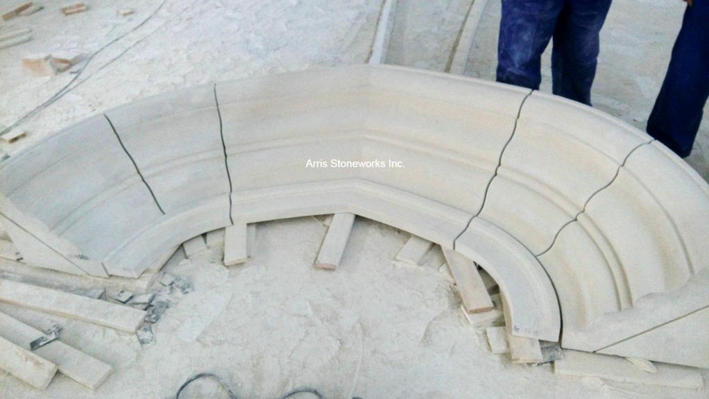 Curved architectural stone assembly in workshop, showcasing precise technical shop drawing coordination and custom stone fitting.