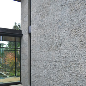 Modern exterior architectural facade clad in textured, large-format Ecru Limestone panels under daytime lighting.