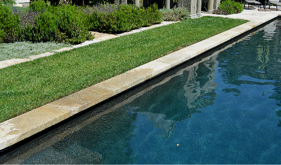 Expansive pool area featuring Gold Beige Granite coping and surrounds, illustrating the stone's durability and elegant golden-beige aesthetic in a sunlit outdoor setting.