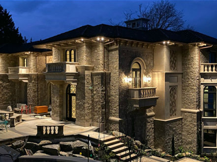 Castle-style residential exterior featuring Glenn Limestone large-scale corbels, wall cladding, radius balustrades, curved door entries, carved under-soffit, massive stone structural columns.