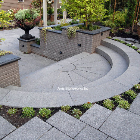 Custom-fabricated circular stone stairs and patio pavers made of Obsidian Basalt with a Lychee finish.