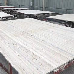 Large-format Argent Grigio Travertine wall panels pre-cut and organized on production skids in a fabrication facility.