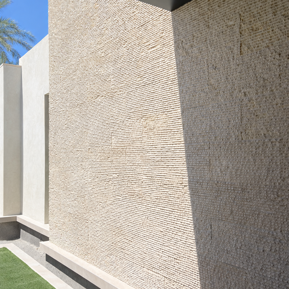 Modern exterior corner showcasing smooth and subtly textured Khaki Limestone wall panels meeting clean architectural lines.