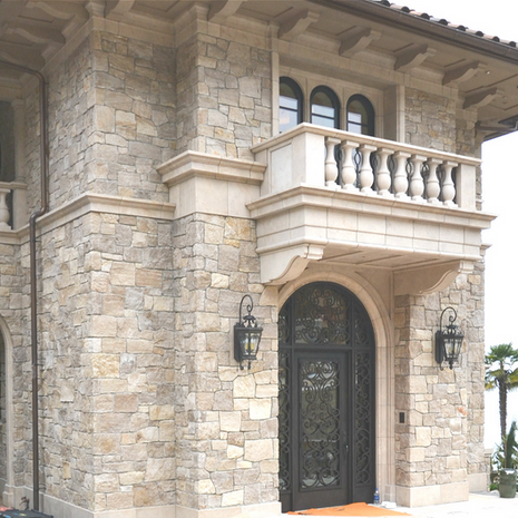 Close-up of a massive custom-carved Glenn Limestone archway featuring a detailed under-soffit and radius door surrounds for a luxury castle-style estate.
