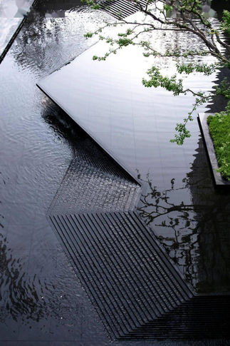 Exterior architectural water feature with a Black Galaxy Granite base, demonstrating how the stone's metallic 'stars' intensify when wet for a dynamic landscape focal point.