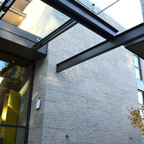 Modern entryway featuring a stone-clad exterior reflected in a perimeter water feature, demonstrating the stone's elegance in wet environments.