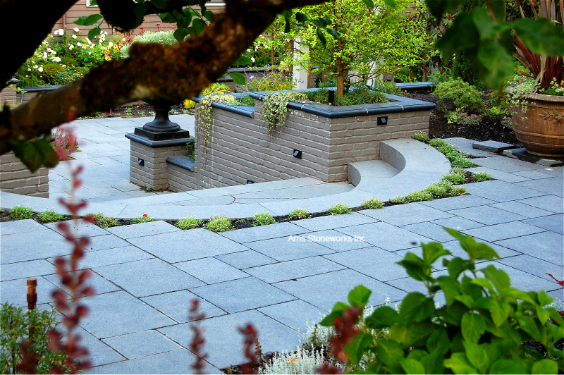 Modern residential landscape with Obsidian Basalt pavers, large section stone stairs, and a sleek water feature with custom stone wall caps.