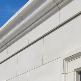 Modern multi-story luxury home featuring an exterior facade clad entirely in light cream Eggshell White limestone panels.