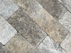 Tumbled and honed Titanium Travertine brick tiles arranged in a staggered pattern showcasing structural grey stone variations.