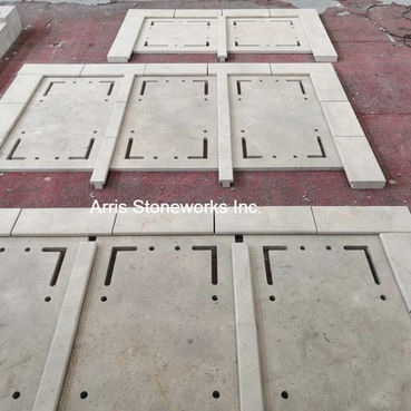 Large format natural stone panels arranged sequentially on a workshop floor with alignment lines for architectural quality control.