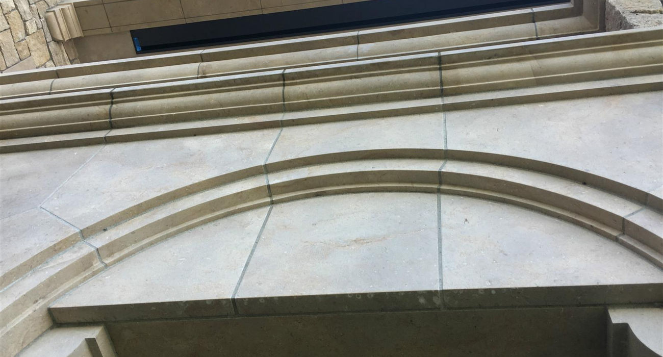 Close-up of the carved radius stone cornice, showcasing the "bone" (structure) and "skin" (honed texture) of the Glenn Limestone.