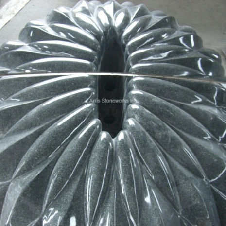Close-up of a polished Sea Green Granite water feature at Moffett Towers, showing deep vertical ridges that create a shimmering, liquid-like texture.