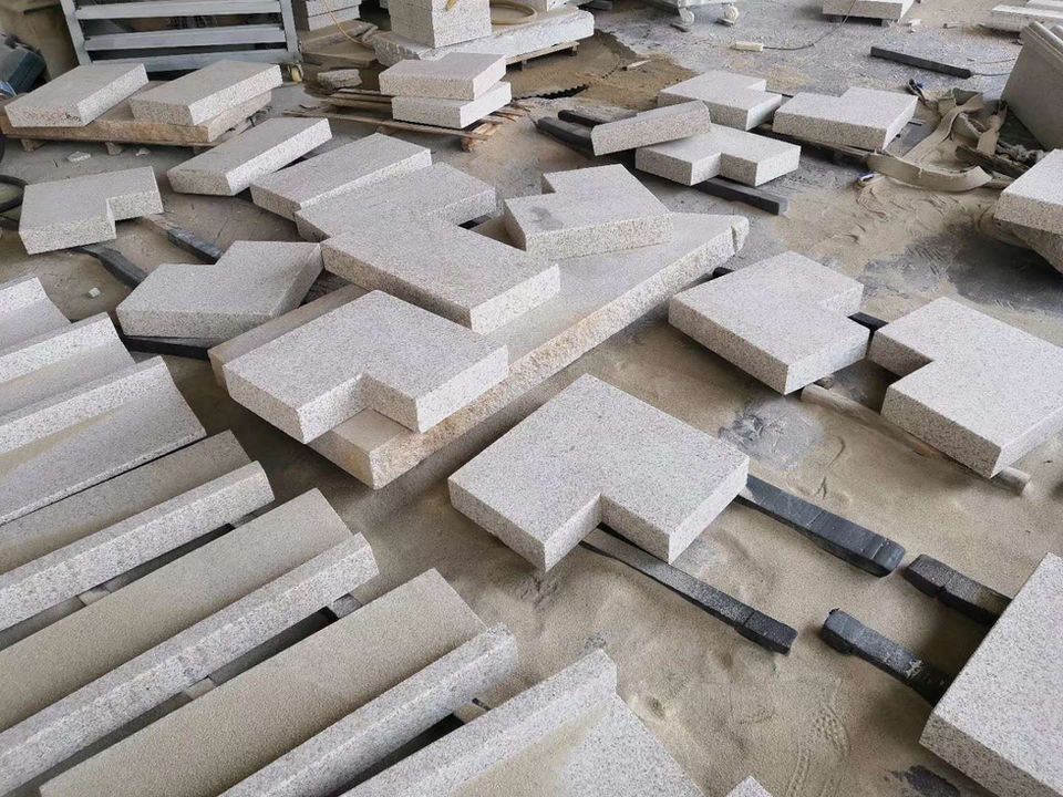 Workshop assembly of Tuscan Granite architectural elements, including thick-cut thresholds and paving slabs, showcasing the stone's warm beige mineral consistency.