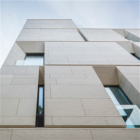 Architectural exterior showcasing interlocking limestone blocks and sleek, geometric window cutouts.